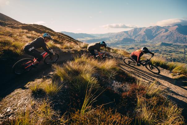 Group of downhill mountain bikers shredding Coronet Peak, Queenstown overlooking valley