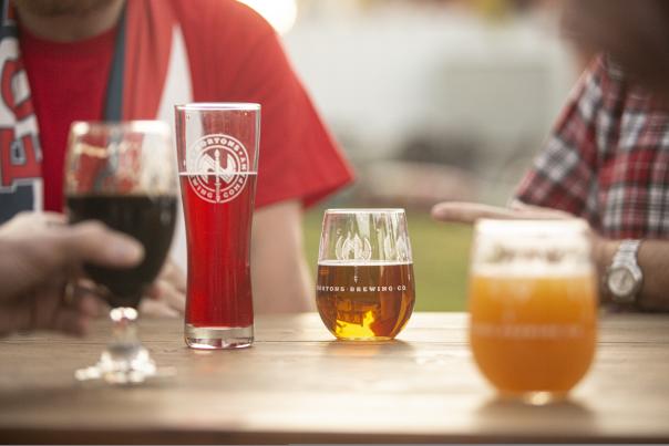 Four beers sit on a table at Wicked Brews Tour while men converse