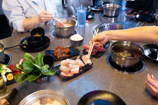 Plates of fresh vegetables, meats, and sauces ready for grilling at KPOT Korean BBQ & Hot Pot.”