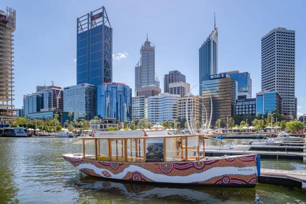 Boat with Indigenous Art in the river in front of the cityscape