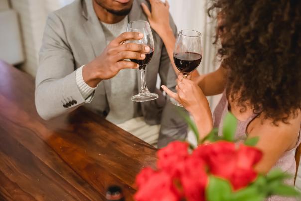African American couple drinking wine, red roses in foreground