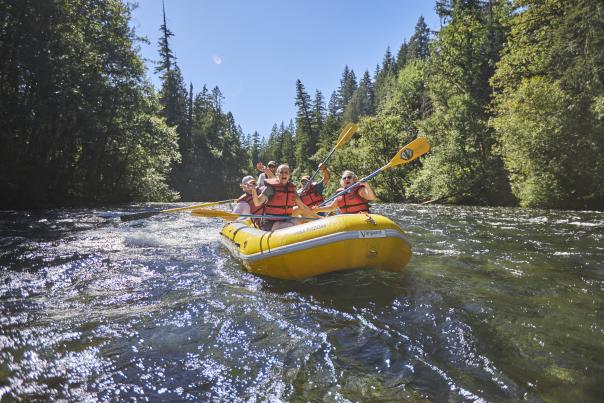 a yellow river raft full of happy rafters floats down the river