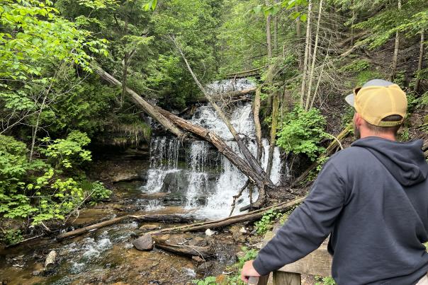A man looking out at Wagner Falls, located in the Upper Peninsula of Michigan