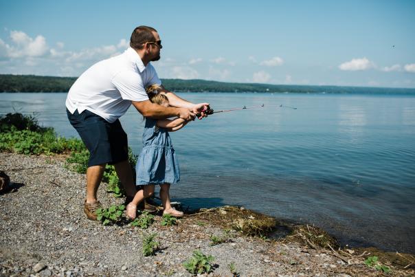father and daughter with fishing pole at lake