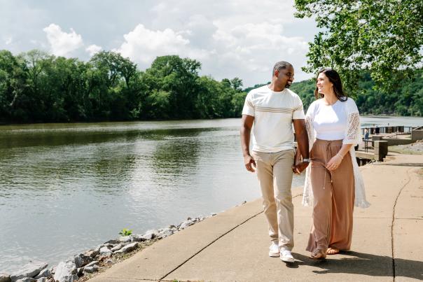 a man and woman walk along a riverside path