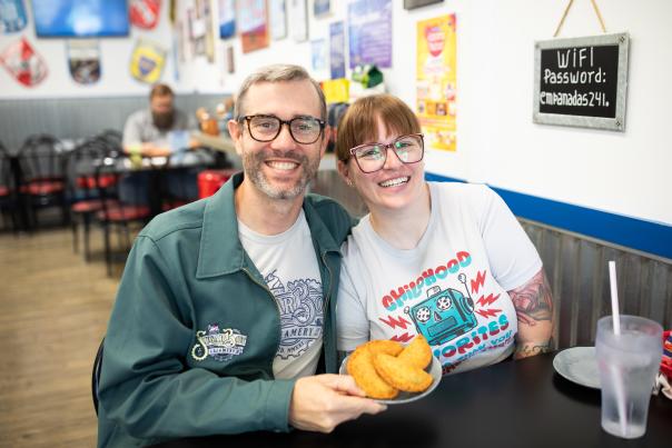 Man and Woman holding up plate of empanadas at restaurant