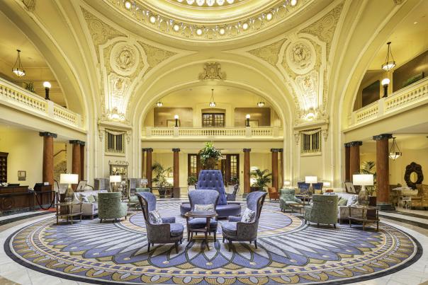 Ornate historical lobby with seating in the middle and a round skylight