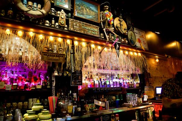 Bar decorated with hula skirts, flags and a skeleton.
