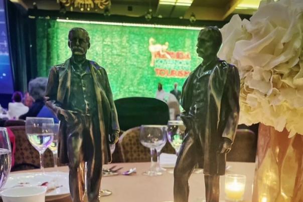 Two Henry Awards displayed on a banquet table. They awards look like miniature statues of Henry Flagler.