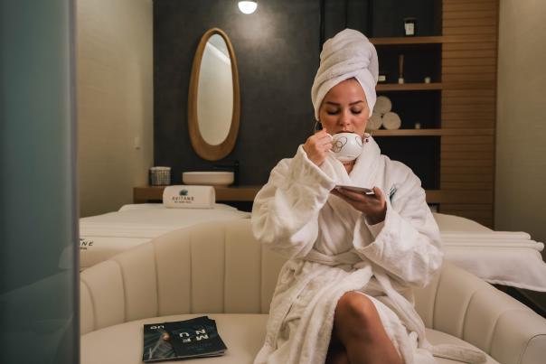 A woman sipping coffee in a bathrobe at a spa
