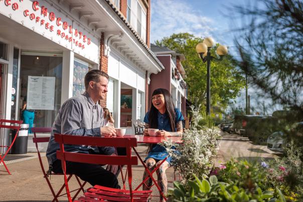 A man and a woman sit at a cafe table outside of Condor Chocolates in Athens, GA.