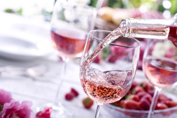 Rose' wine being poured into a wine glass on a pink and white table setting
