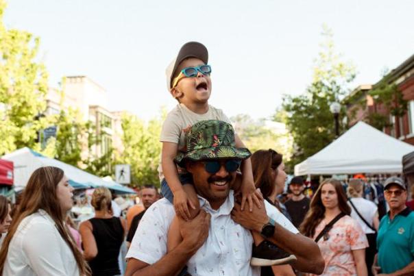 A Dad holding his kid on his shoulders in a crowd.