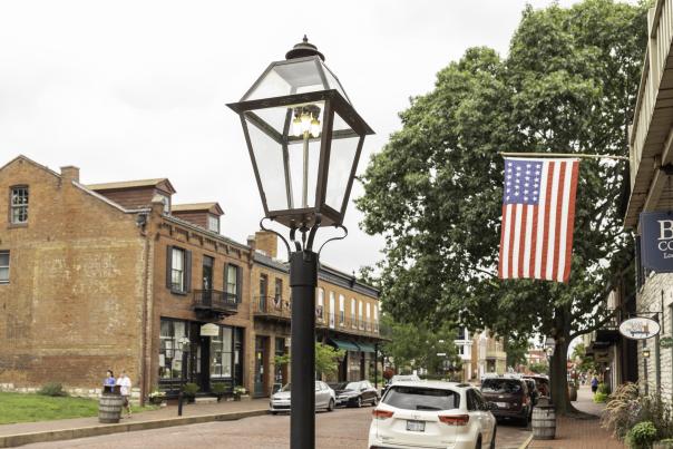 A victorian lamppost on Historic Main Street with red brick buildings and an American flag in the background.