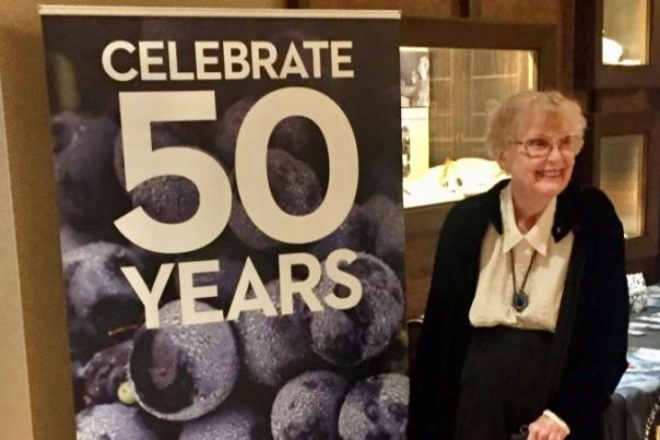 Audrey Cilurzo poses with a sign celebrating 50 years
