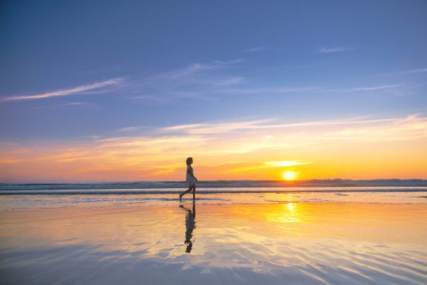 Lady walking on the beach at sunrise