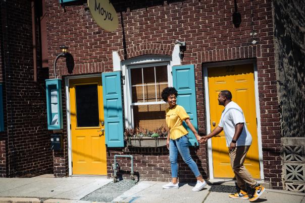 A couple walks along a street with colorful doorways in historic Jim Thorpe, PA in the Poconos.