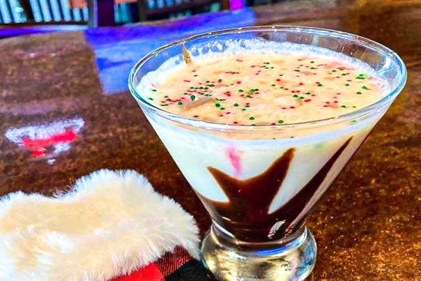 A peppermint martini sits next to a plaid stocking