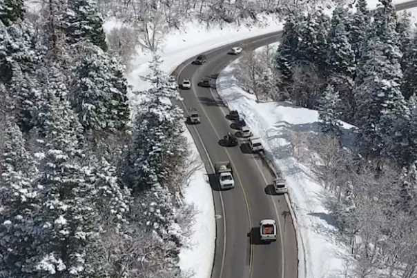 Cars driving on a slightly wet road in a snowy canyon