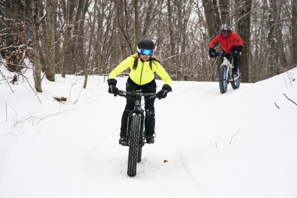 Two people biking through snowy trails