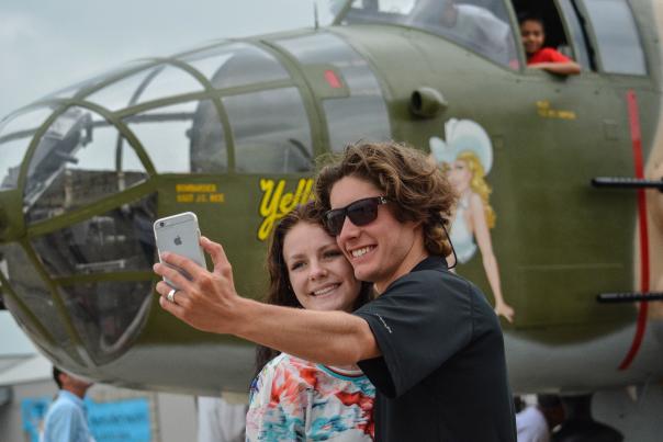 Young couple taking selfie with WWII plane