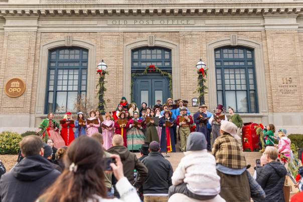 A group of carolers sing on the steps of the Old Post Office as a crowd watches on Historic Main Street in St. Charles, Missouri.