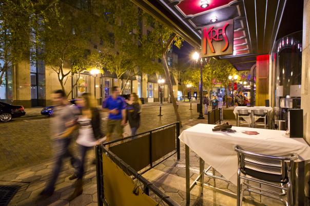 People walking by Kres restaurant at Church Street Station in downtown Orlando at night