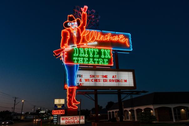 A neon sign for the Winchester Drive-In Theatre in Oklahoma City, featuring a cowboy figure and colorful lettering.
