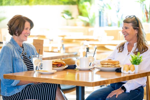 Hope Breakfast Bar featuring two friends seated at a table with pancakes for breakfast.