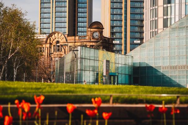 High rise buildings in Manchester with a park and flowers in the foreground