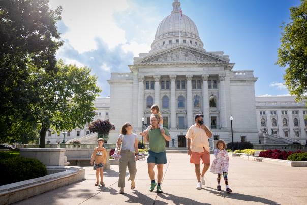 Young children and adult tourists exploring the Capitol Building grounds and things to do in Madison WI