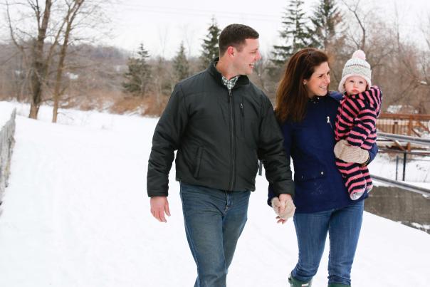Couple with Baby Holding Hands and Walking through the Snow