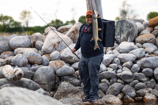 Man shore fishing on Devils Lake, ND holding a Northern Pike