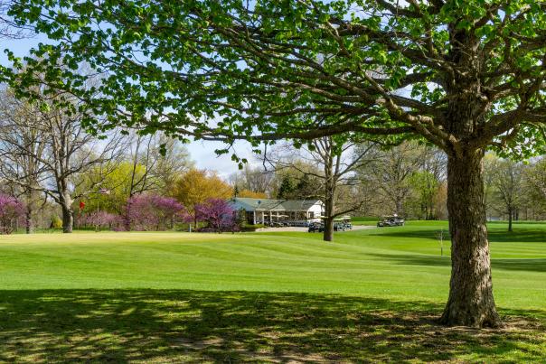 Sprawling greens with purple flowering trees and the golf club house are shown at Shoaff Park's Golf Course in Fort Wayne, Indiana