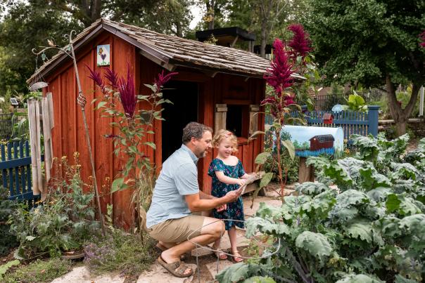 Father and Daughter looking at a map at the Bell Children's Garden in Green Bay, Wisconsin with the garden scenery in the background.