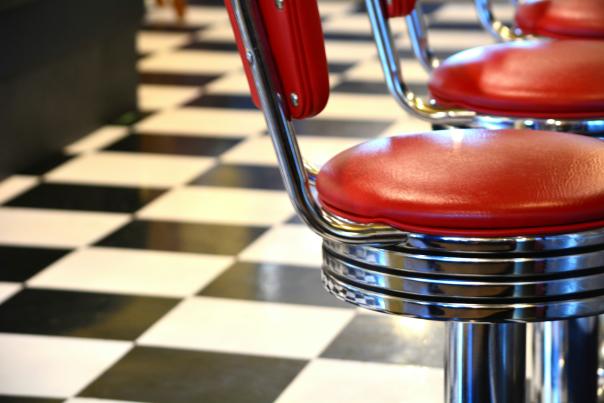 A checkerboard floor and a barstool at a diner restaurant