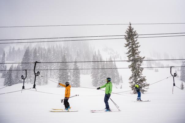 Two skiers on Alta's rope tow with chairlift lines in the background