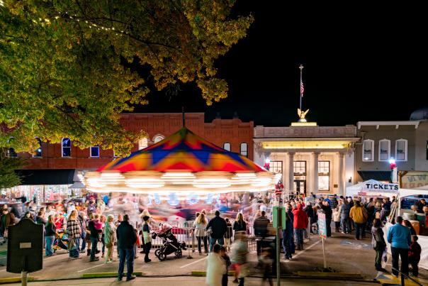 The brightly lit carousel spins surrounded by festival goers at Home for the Holidays on the downtown square.