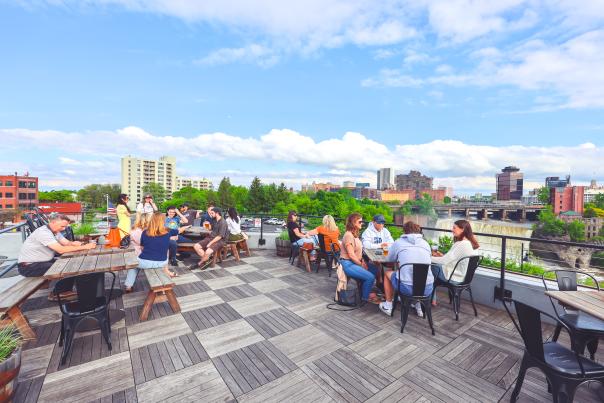 Outdoor dining at Genesee Brew House with view of High Falls and downtown Rochester, NY skyline
