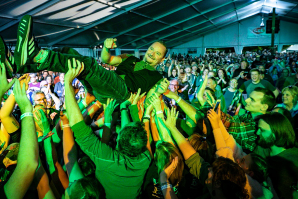 lead singer from the band gaelic storm is hoisted by the crowd at Michigan irish music festival over their heads