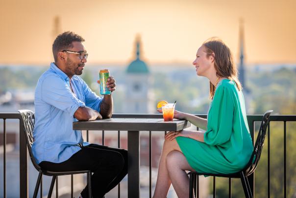 A man and woman drink cocktails at a table at the rooftop bar of Hybar.