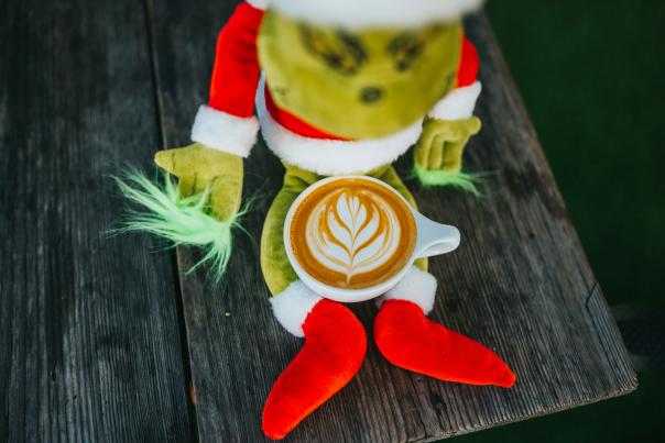 A Grinch ornamenet with a coffee cup