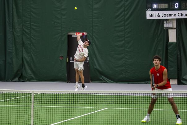 Tennis player throwing the ball up in the air and preparing to hit it