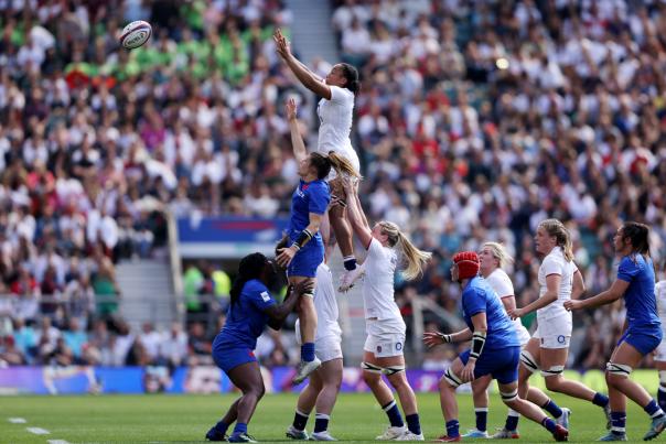 Rugby players lifting up teammate to catch a ball