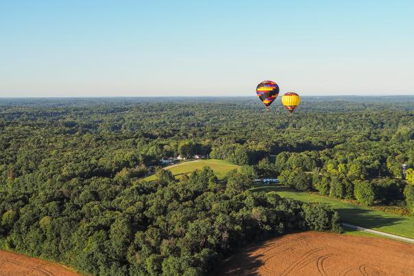 Two hot air balloons floating over Bloomington's rolling hills