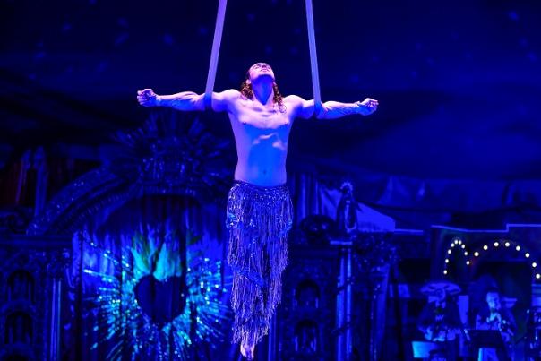 An aerial performer hangs from ribbons from the ceiling