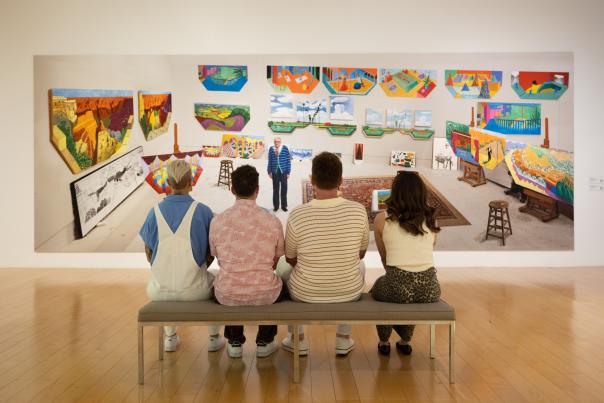 Four people sitting on a bench looking at a painting at the Palm Springs Art Museum.