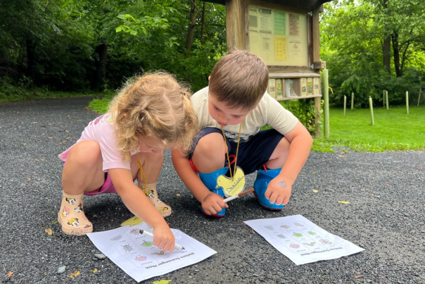 Two children outside in the park working on a scavenger hunt
