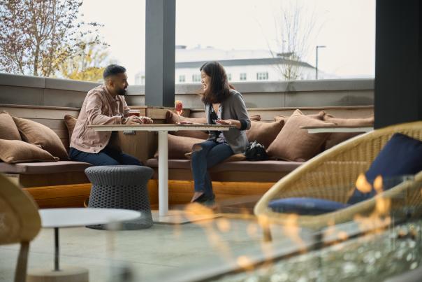 "Two guests relax with refreshing cocktails on the outdoor patio at Toscana Kitchen & Wine Market, perfect for a warm evening out.