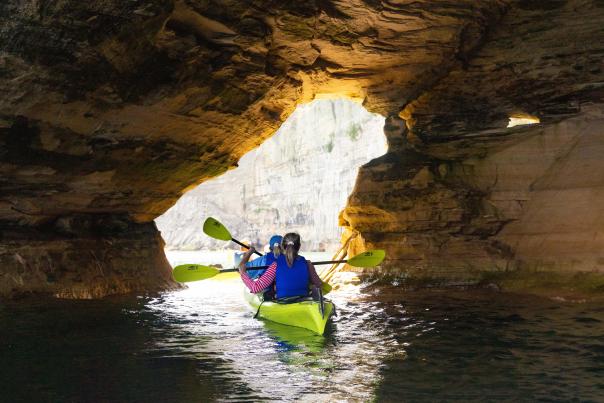 Two individuals kayaking in a sea cave in Pictured Rocks National Lakeshore.